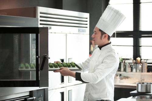 Chef arranging food trays in a convection oven 