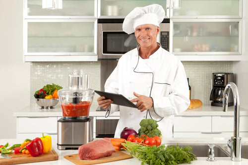 Chef showcasing commercial food processor with a mix of ingredients inside.