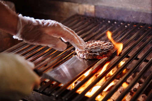 A delicious burger patty being flipped on a grill.