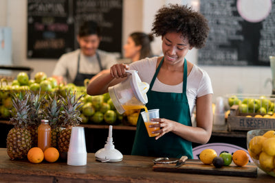 Woman pouring juice into a glass from a citrus juicer