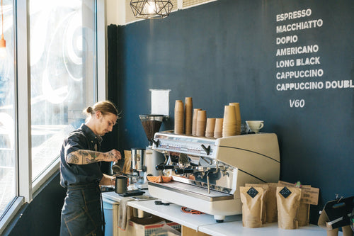 Cafe Owner Making Coffee on a Commercial 3 Group Coffee Machine